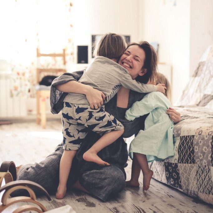 happy mom with two children on the floor in the room. concept motherhood and trust, toning and life style